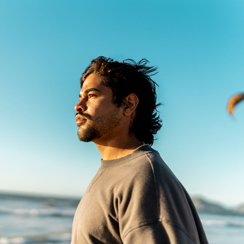 A person standing near the ocean in sunlight.